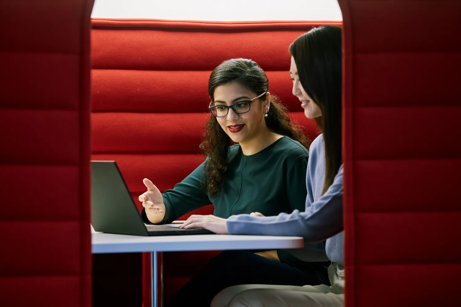 Duas colegas conversando diante de um notebook em uma cabine vermelha do escritório da Henkel em Singapura